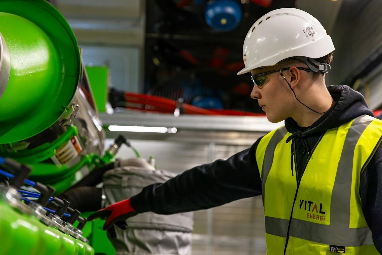 Engineer in helmet and safety vest working with industrial equipment